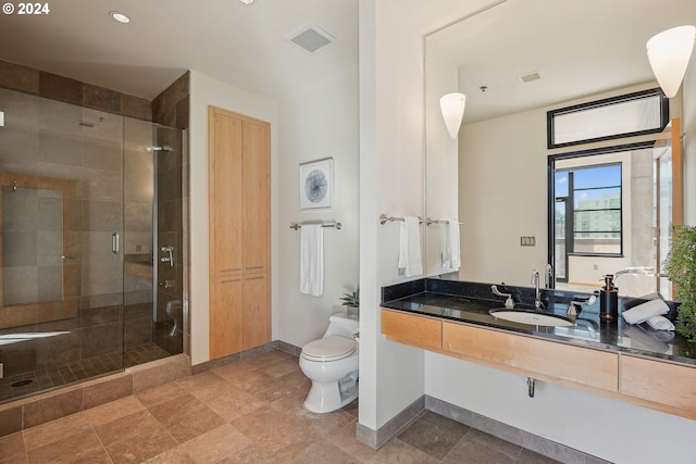 bathroom with vanity, toilet, and a shower with door