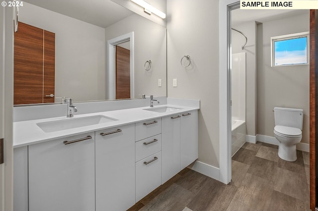 full bathroom featuring vanity, hardwood / wood-style floors, washtub / shower combination, and toilet