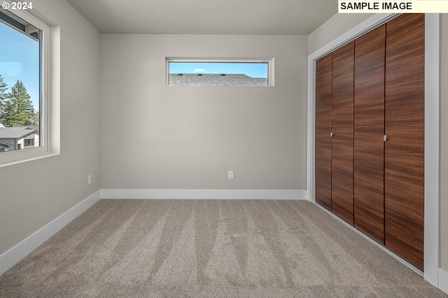 unfurnished bedroom with light carpet, multiple windows, and a closet