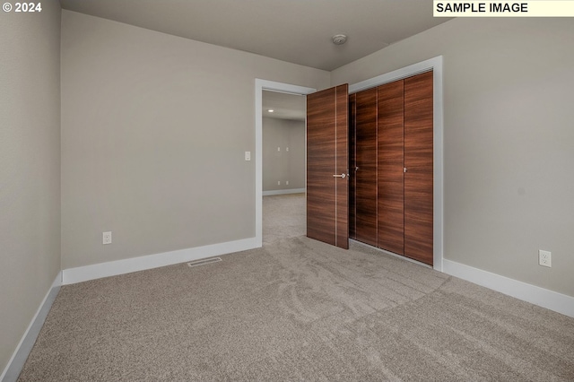 unfurnished bedroom with a closet and light colored carpet