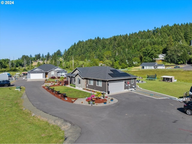 view of front of property featuring solar panels, a garage, and a front lawn