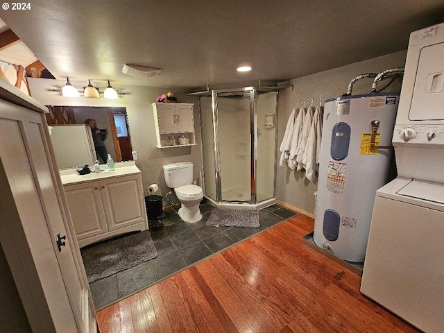 bathroom with stacked washing maching and dryer, water heater, an enclosed shower, vanity, and hardwood / wood-style flooring