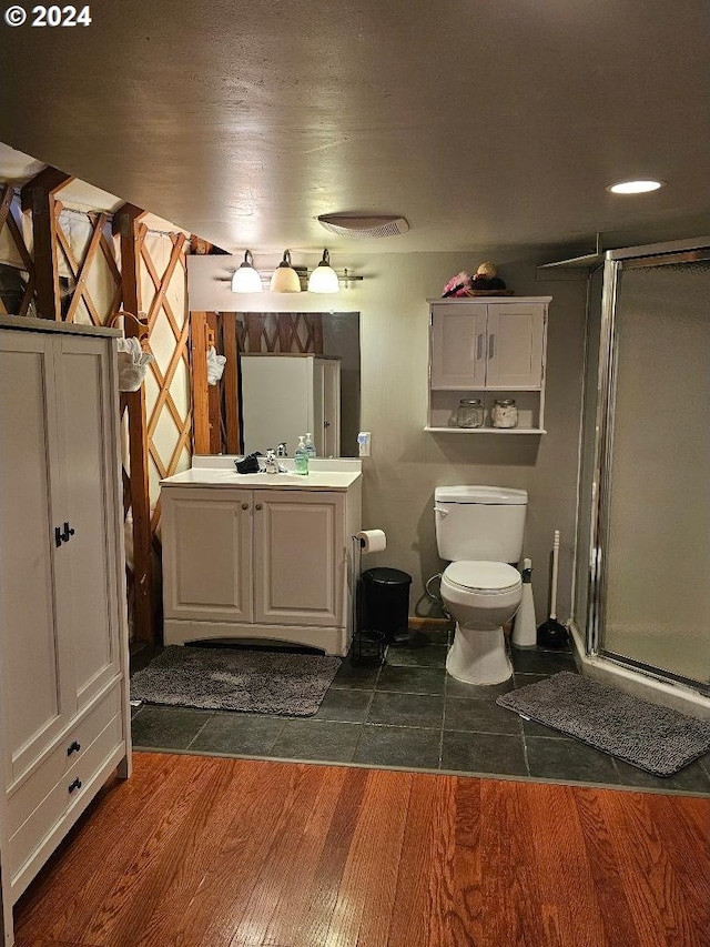 bathroom featuring toilet, vanity, an enclosed shower, and hardwood / wood-style flooring