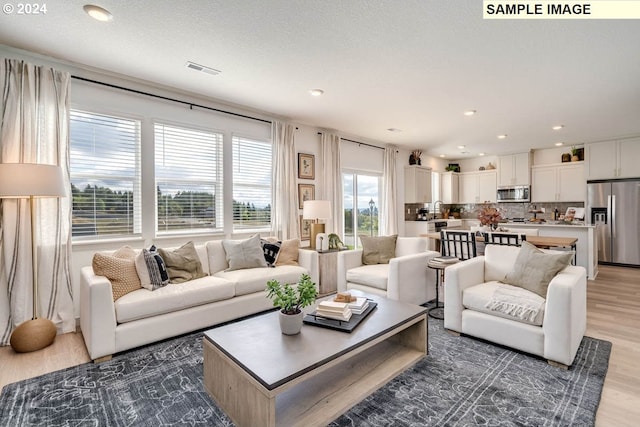 living room with visible vents, light wood-style flooring, and recessed lighting