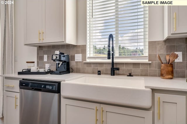 kitchen with tasteful backsplash, light countertops, white cabinetry, a sink, and dishwasher