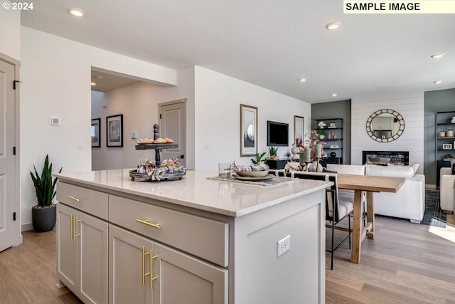 kitchen with a large fireplace, a center island, gray cabinetry, and light hardwood / wood-style flooring