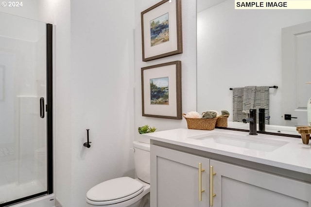 bathroom featuring a shower with door, vanity, and toilet