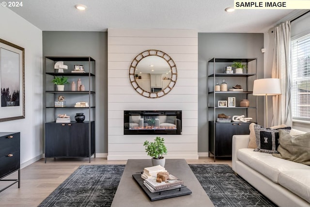 living room featuring a fireplace, light wood-type flooring, and a textured ceiling