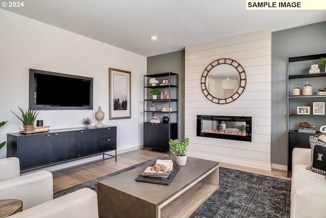 living room featuring a textured ceiling, a fireplace, wood finished floors, and baseboards