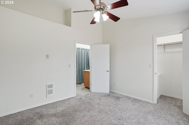 unfurnished bedroom featuring light carpet, heating unit, ceiling fan, a closet, and a high ceiling