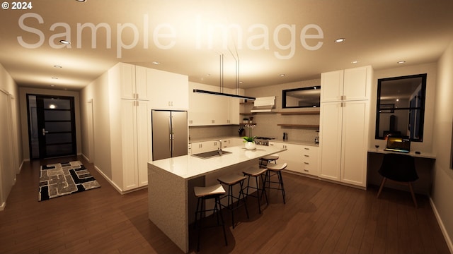 kitchen featuring sink, stainless steel fridge, a kitchen bar, a kitchen island with sink, and white cabinets