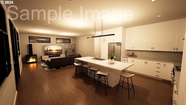 kitchen featuring white cabinetry, stainless steel fridge, a breakfast bar area, and a kitchen island with sink