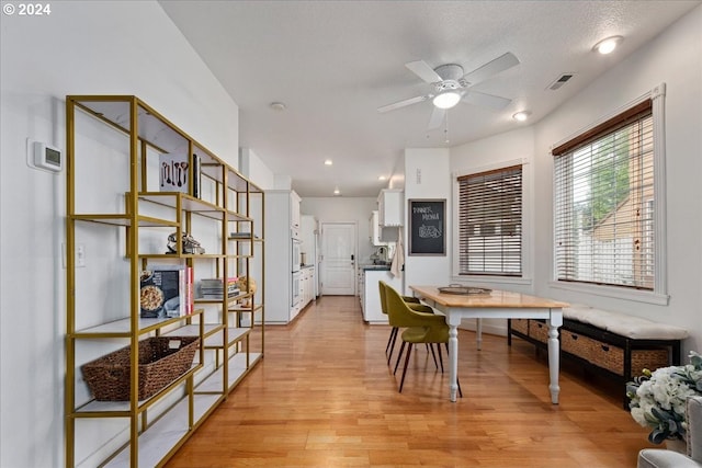 dining area featuring ceiling fan, light hardwood / wood-style floors, and a textured ceiling