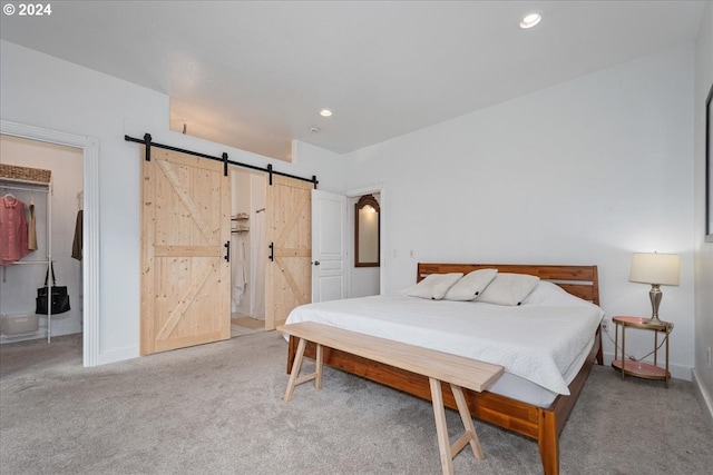 bedroom featuring a barn door, light colored carpet, and a closet