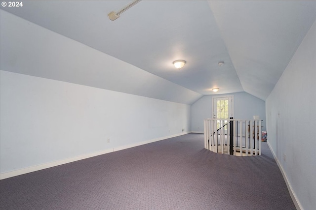 additional living space featuring dark carpet and lofted ceiling