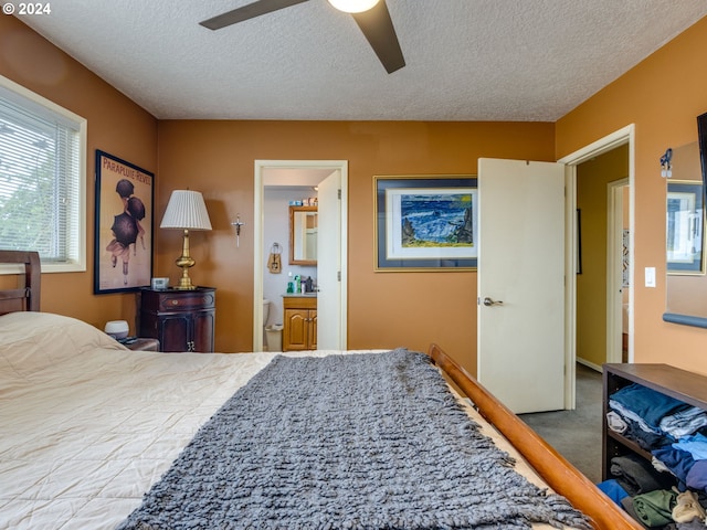 bedroom featuring ceiling fan, carpet floors, a textured ceiling, and ensuite bath