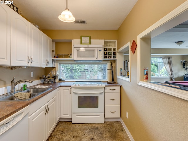 kitchen featuring white appliances, white cabinetry, hanging light fixtures, and sink