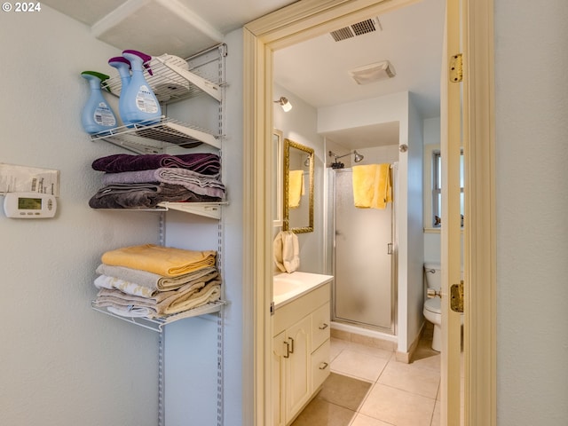 bathroom with tile patterned floors, vanity, toilet, and a shower with shower door