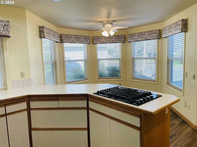 kitchen featuring kitchen peninsula, gas cooktop, ceiling fan, white cabinets, and plenty of natural light