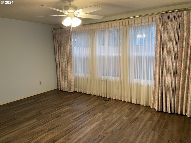 empty room with ceiling fan, dark hardwood / wood-style floors, and a textured ceiling