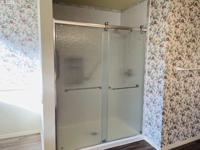 bathroom with wood-type flooring and a shower with shower door