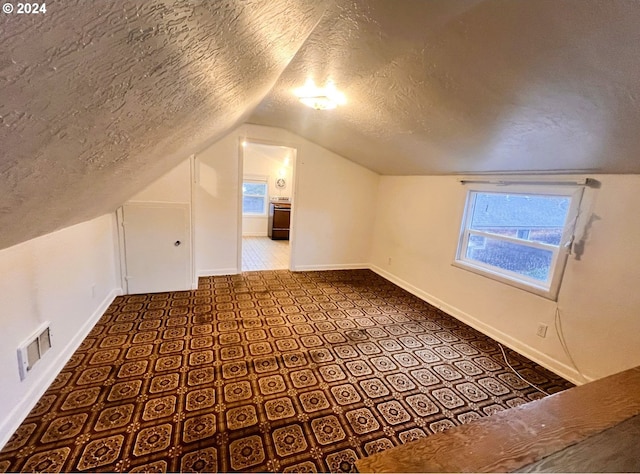 additional living space with a textured ceiling and vaulted ceiling