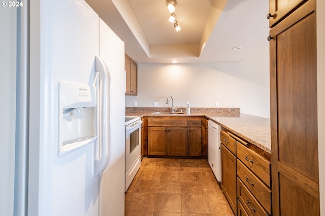 kitchen featuring white appliances, sink, a barn door, a tray ceiling, and kitchen peninsula