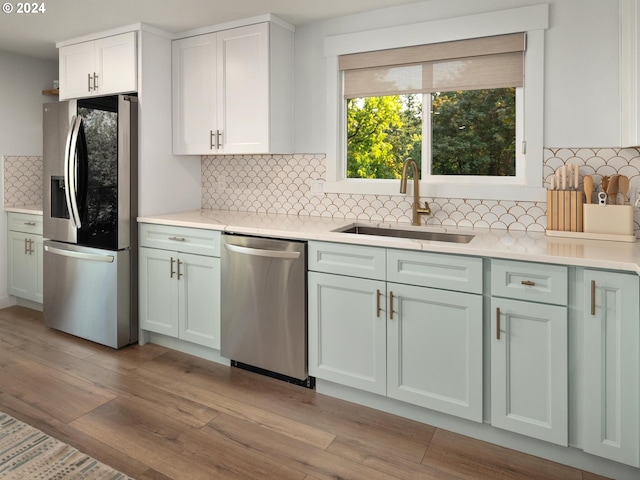 kitchen featuring appliances with stainless steel finishes, white cabinetry, light hardwood / wood-style flooring, and tasteful backsplash