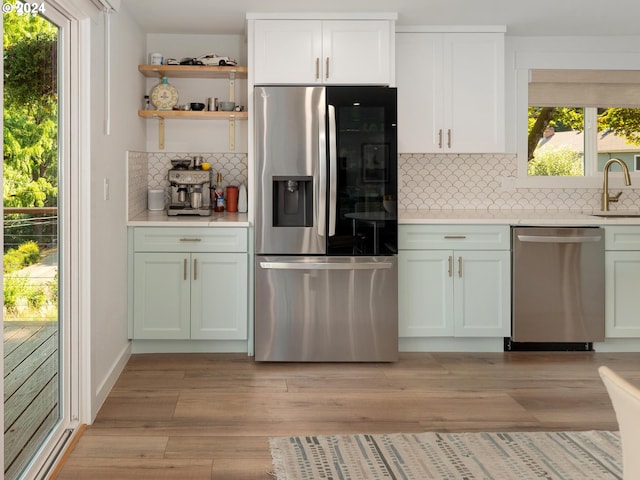 kitchen featuring tasteful backsplash, sink, white cabinetry, light hardwood / wood-style flooring, and appliances with stainless steel finishes