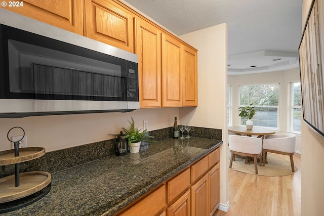 kitchen featuring dark stone counters, a textured ceiling, and light wood-type flooring