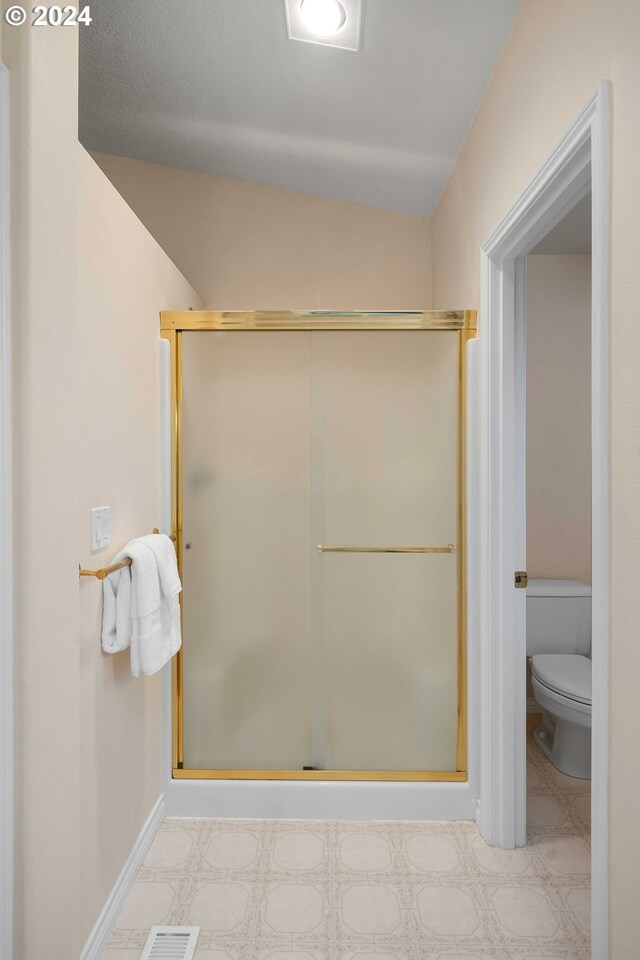 bathroom with a shower with door and toilet