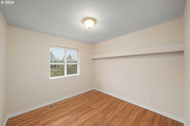 unfurnished room with hardwood / wood-style flooring and a textured ceiling