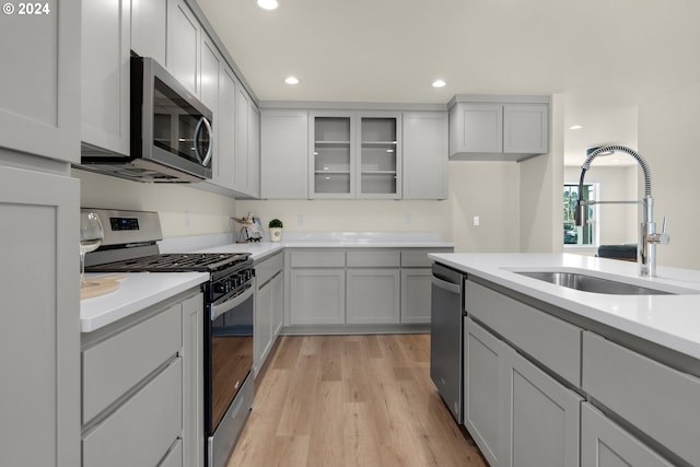kitchen with stainless steel appliances, a sink, light wood-type flooring, light countertops, and recessed lighting