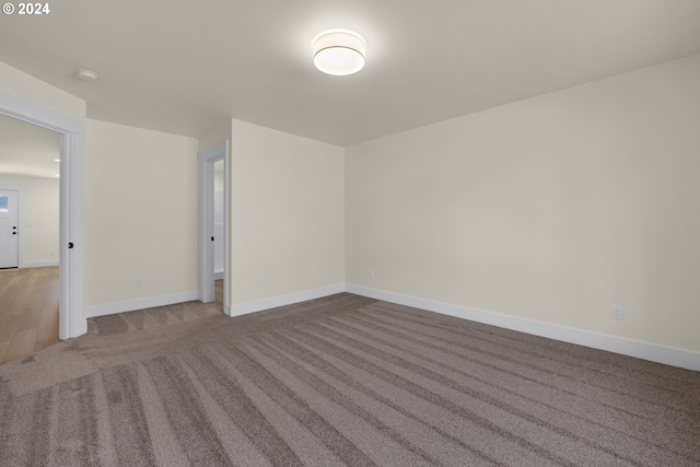 spare room with carpet flooring, baseboards, and a smoke detector