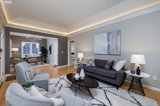 living room featuring a raised ceiling, ceiling fan, and light wood-type flooring