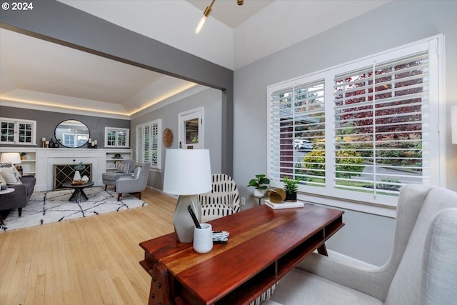 office area with hardwood / wood-style floors and a raised ceiling