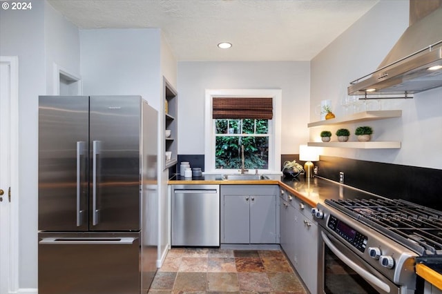 kitchen featuring appliances with stainless steel finishes, sink, gray cabinets, and wall chimney range hood