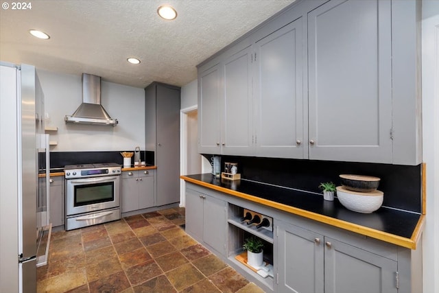 kitchen with appliances with stainless steel finishes, a textured ceiling, gray cabinets, and wall chimney exhaust hood