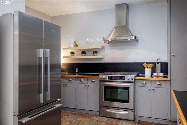 kitchen with gray cabinets, wall chimney range hood, and appliances with stainless steel finishes