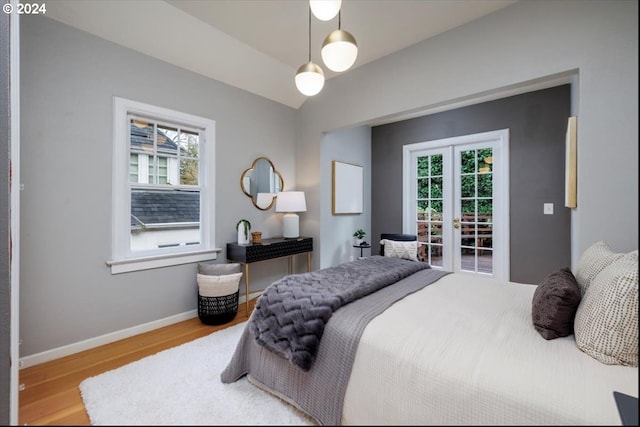 bedroom featuring french doors, lofted ceiling, and hardwood / wood-style flooring