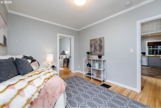 bedroom with sink, wood-type flooring, and crown molding