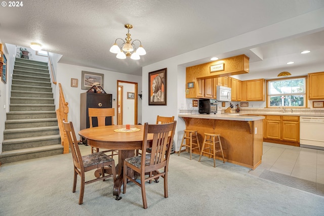 dining space with light carpet, a notable chandelier, sink, and a textured ceiling