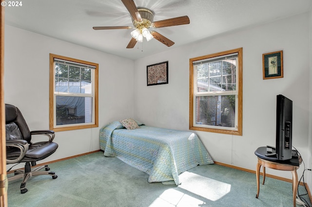 bedroom featuring ceiling fan, light colored carpet, and multiple windows