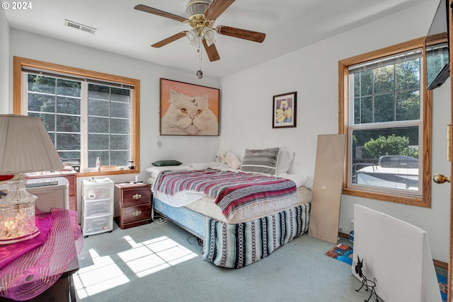 carpeted bedroom featuring ceiling fan and multiple windows