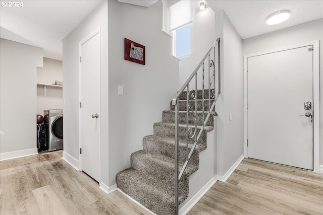 stairs with washing machine and dryer and hardwood / wood-style flooring