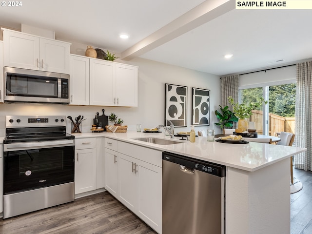 kitchen with hardwood / wood-style floors, kitchen peninsula, sink, and stainless steel appliances