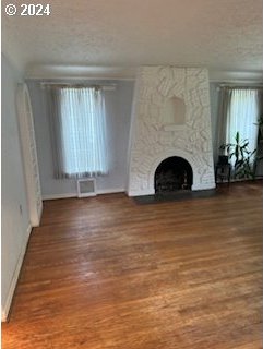 unfurnished living room with a large fireplace, hardwood / wood-style floors, and a textured ceiling