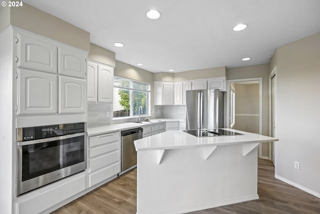 kitchen with hardwood / wood-style flooring, a kitchen island, white cabinetry, and appliances with stainless steel finishes