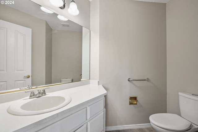 bathroom with hardwood / wood-style floors, vanity, and toilet