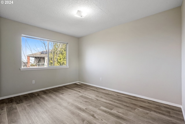 empty room with hardwood / wood-style floors and a textured ceiling